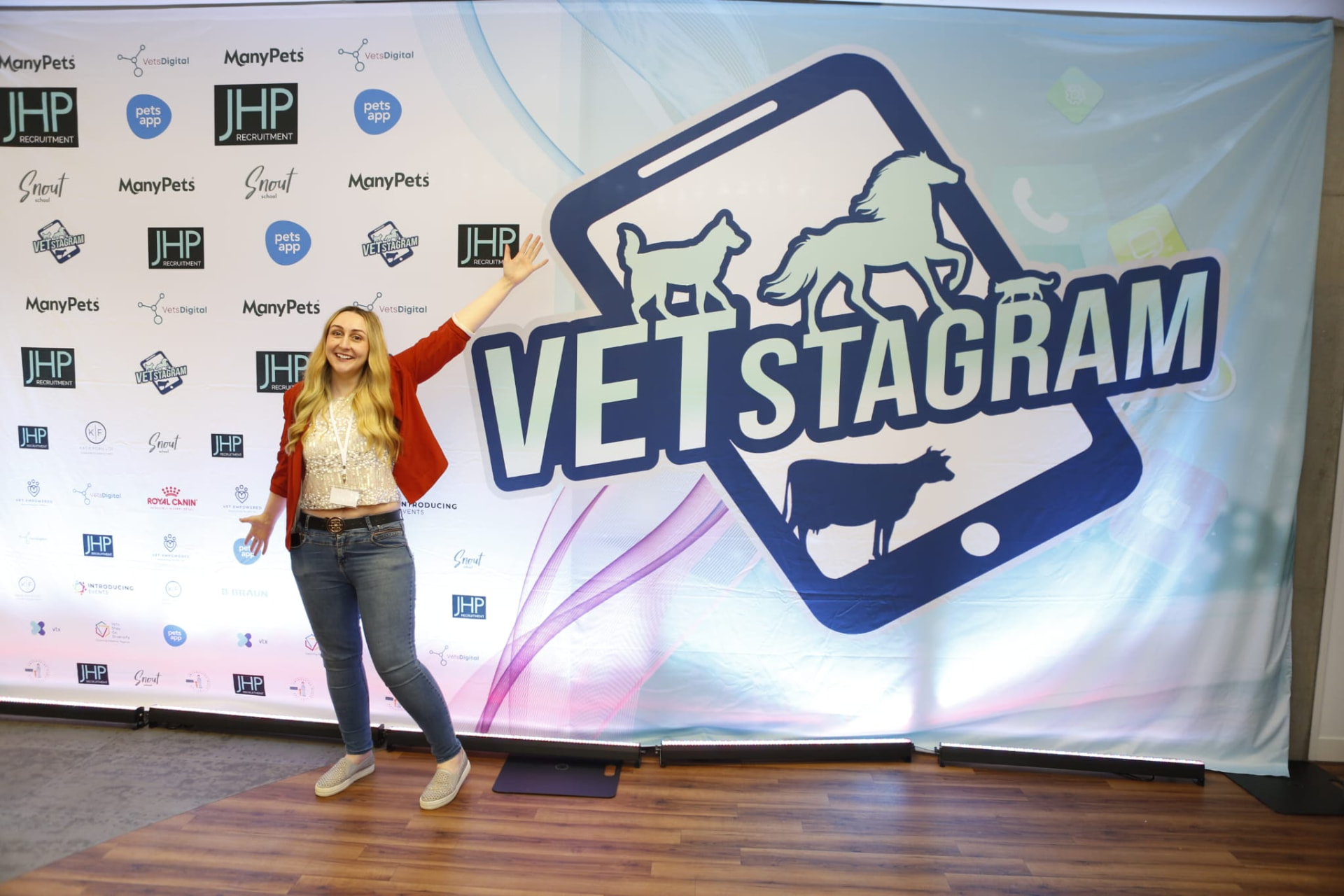 A delegate posing in front of the sponsored VETstagram media wall