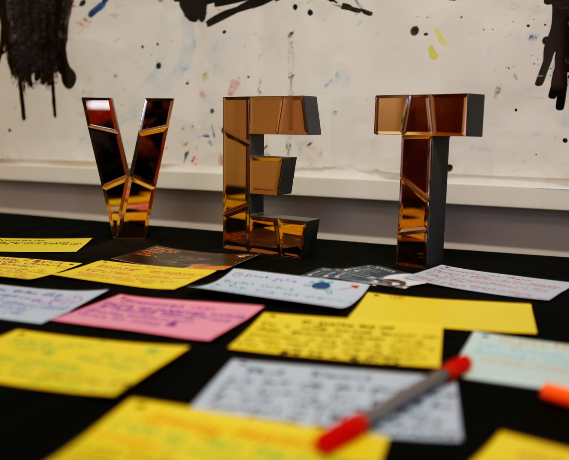 Mirrored VET letters on a table covered in handwritten delegate notes at VETstagram
